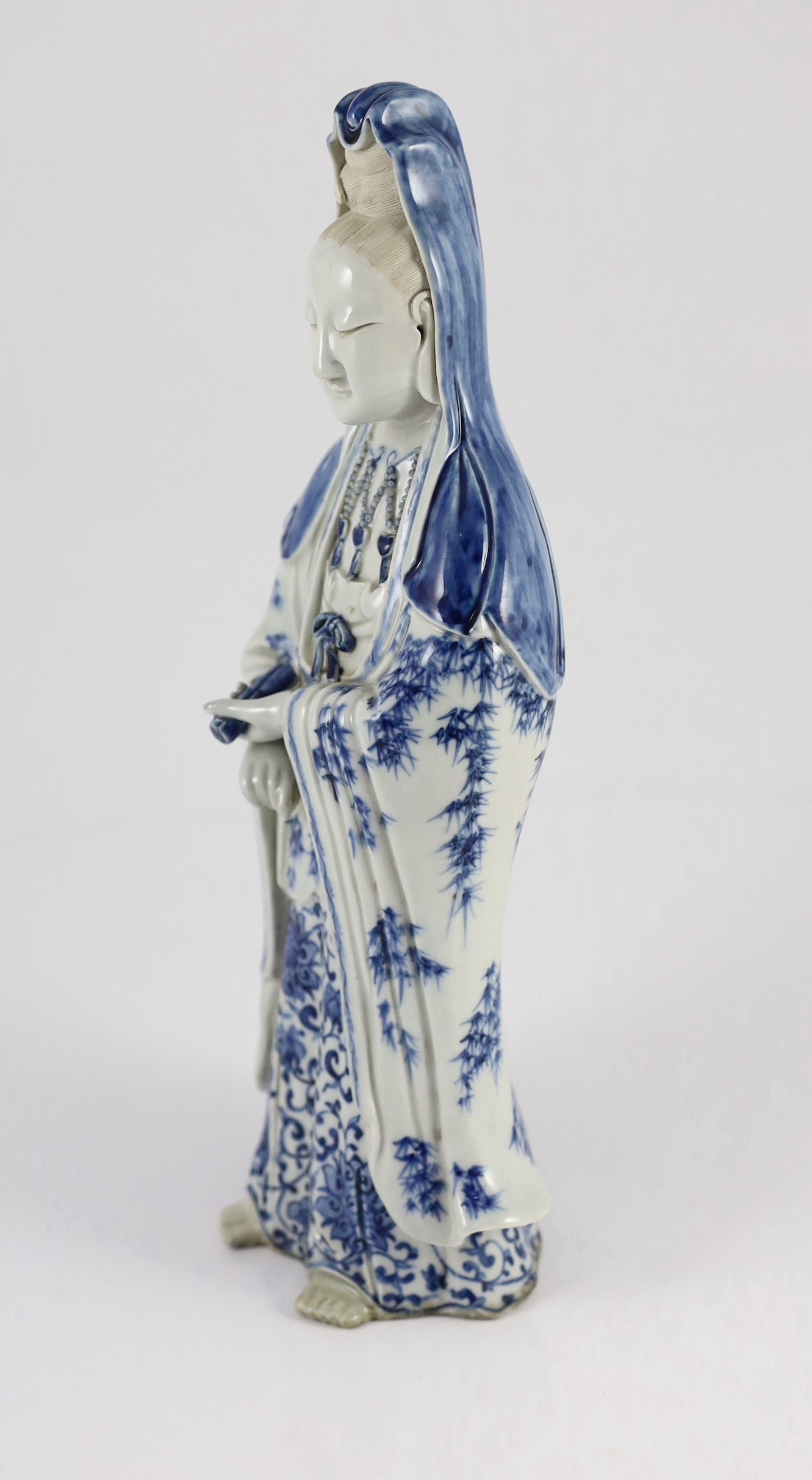 A Chinese blue and white standing figure of Guanyin, late 19th century, 34.5cm high, restoration to left foot